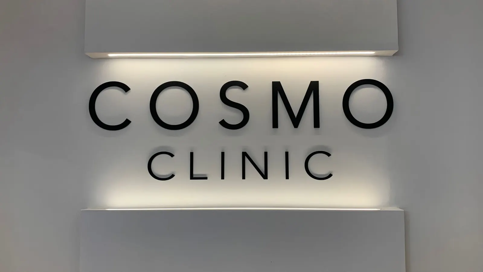 Letreiro iluminado da Cosmo Clinic na parede da clínica