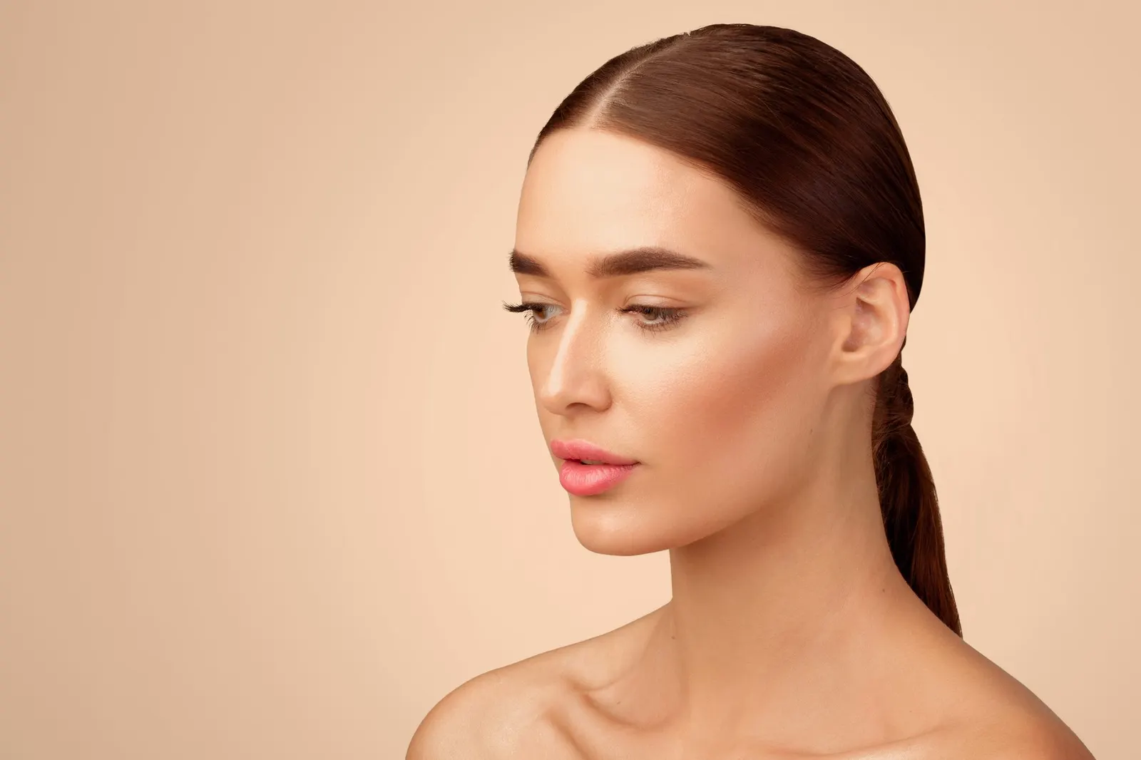 Profile of a woman with brown hair tied back, facial contour