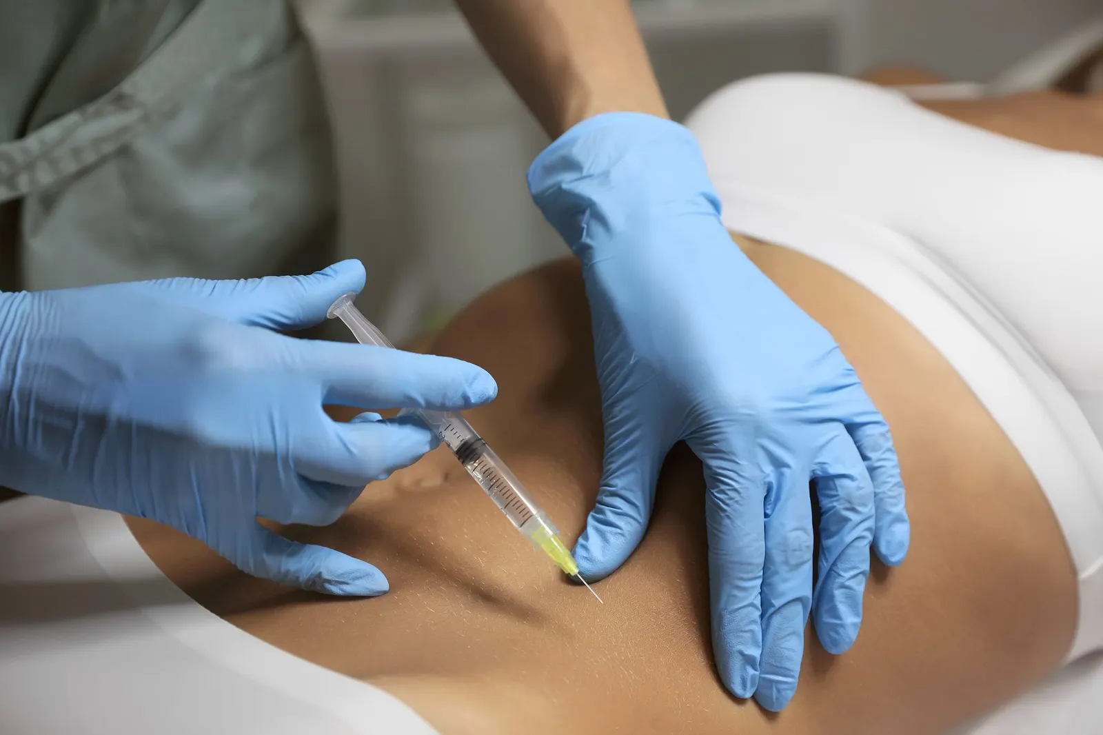 Injection at the hip area, patient lying down, gloved hands